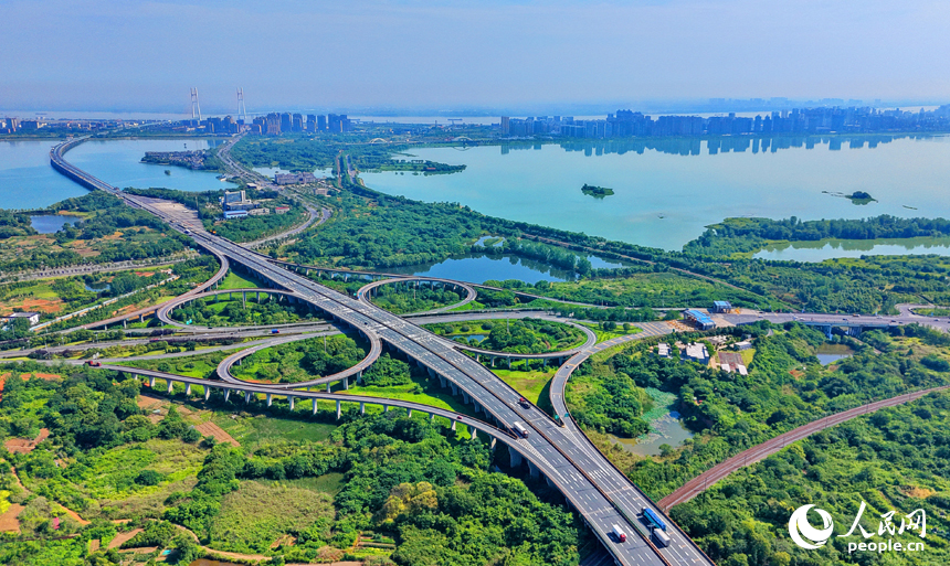 九江市八里湖新区，高速公路、城际高铁、城市道路和环湖公路等交通通道如银龙穿翠纵横交错，与河湖、草木、房屋相映成趣，构成一幅路畅景美的夏日山水城乡画卷。人民网记者 朱海鹏摄