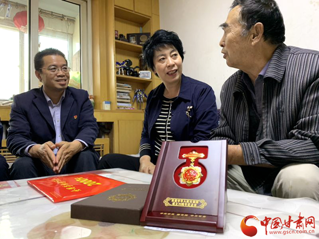 兰州局集团工会主席金霞和兰州西机务段党委书记武文炜给获得勋章的老