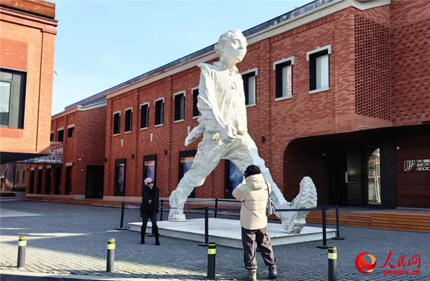 游客在天美艺术街区入口处的巨型雕塑旁拍照留念。人民网记者 李丹摄